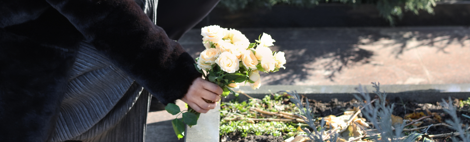 Couple putting flowers on grave of their relative at funeral